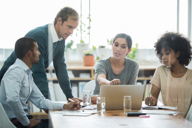 4 employees sitting around a laptop having a discussion