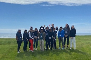 Group of employees with the ocean behind them volunteering at a golf event